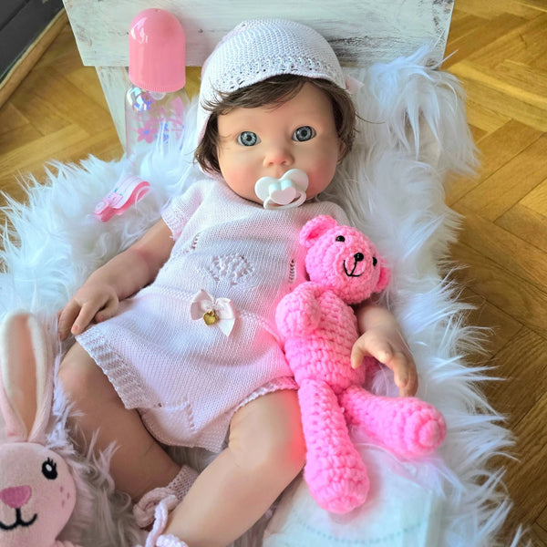 Lorea, la Bebe reborn silicona, tumbada en su cuna con osito y conejito de peluche rosa