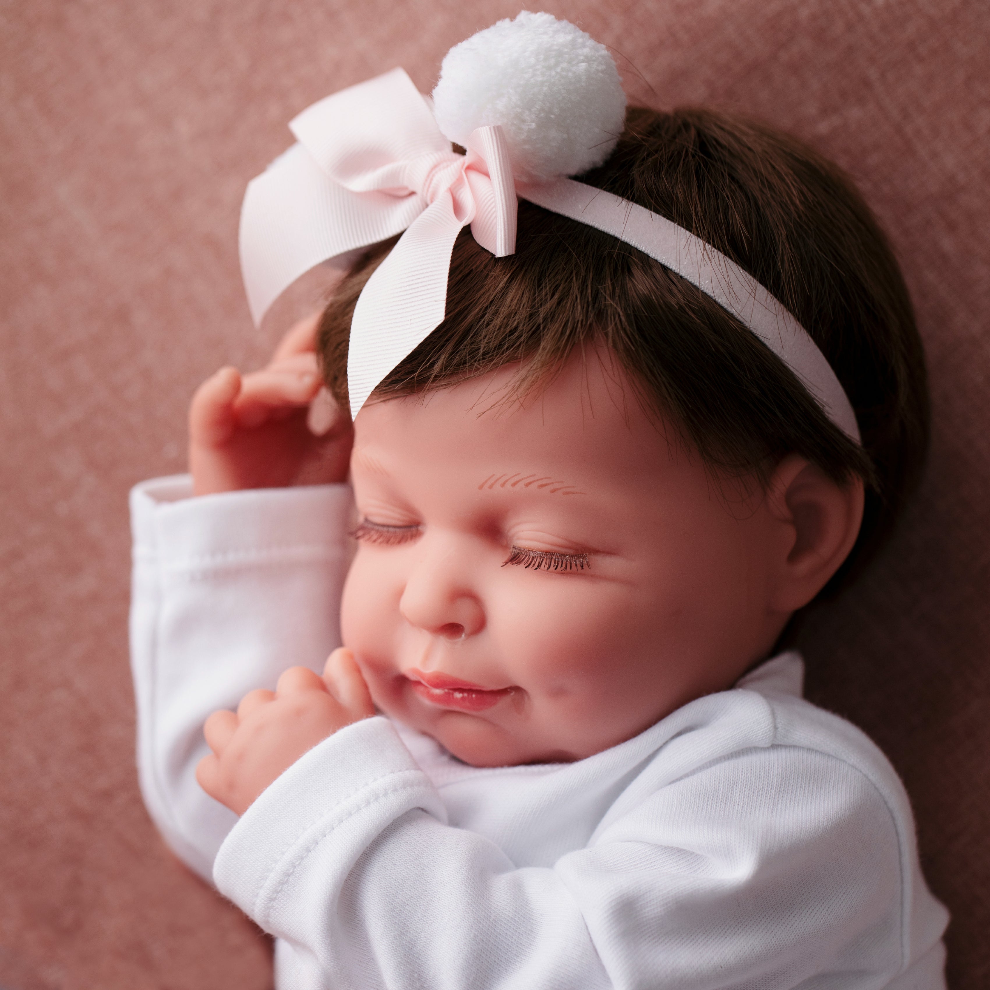 Bebé tipo reborn con los ojos cerrados y diadema rosa 73,49 €